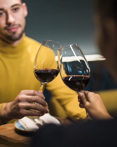 man-woman-clanging-glasses-wine-sitting-table